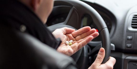 Man driving while holding pills