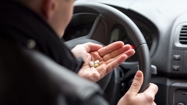 Man driving while holding pills